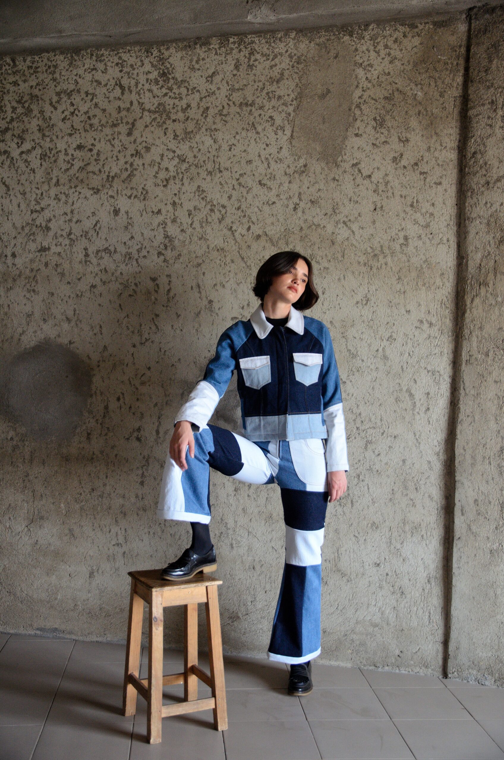 Doria jacket in blue patchwork denim worn in a full silhouette, defined by contrast paneling
