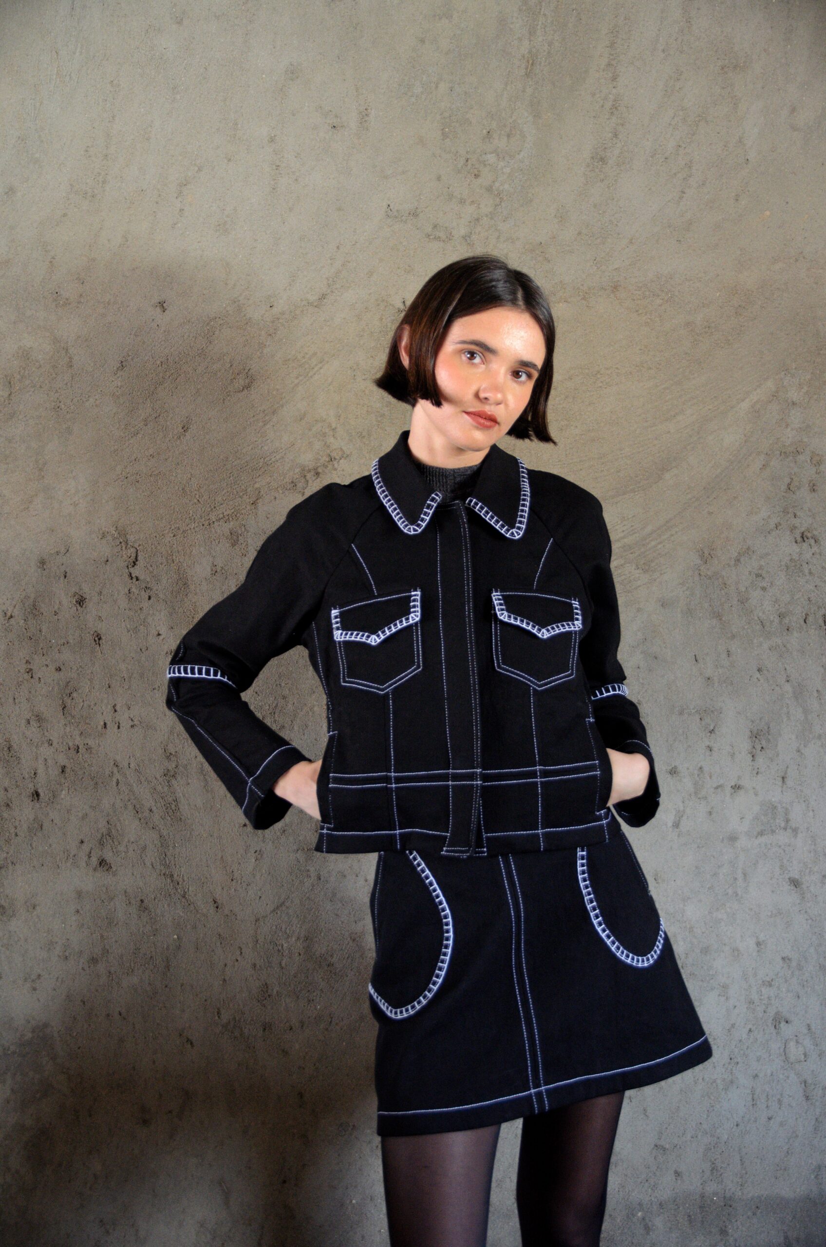 Veste Lova noire en denim avec surpiqûres contrastées blanches portée par un mannequin