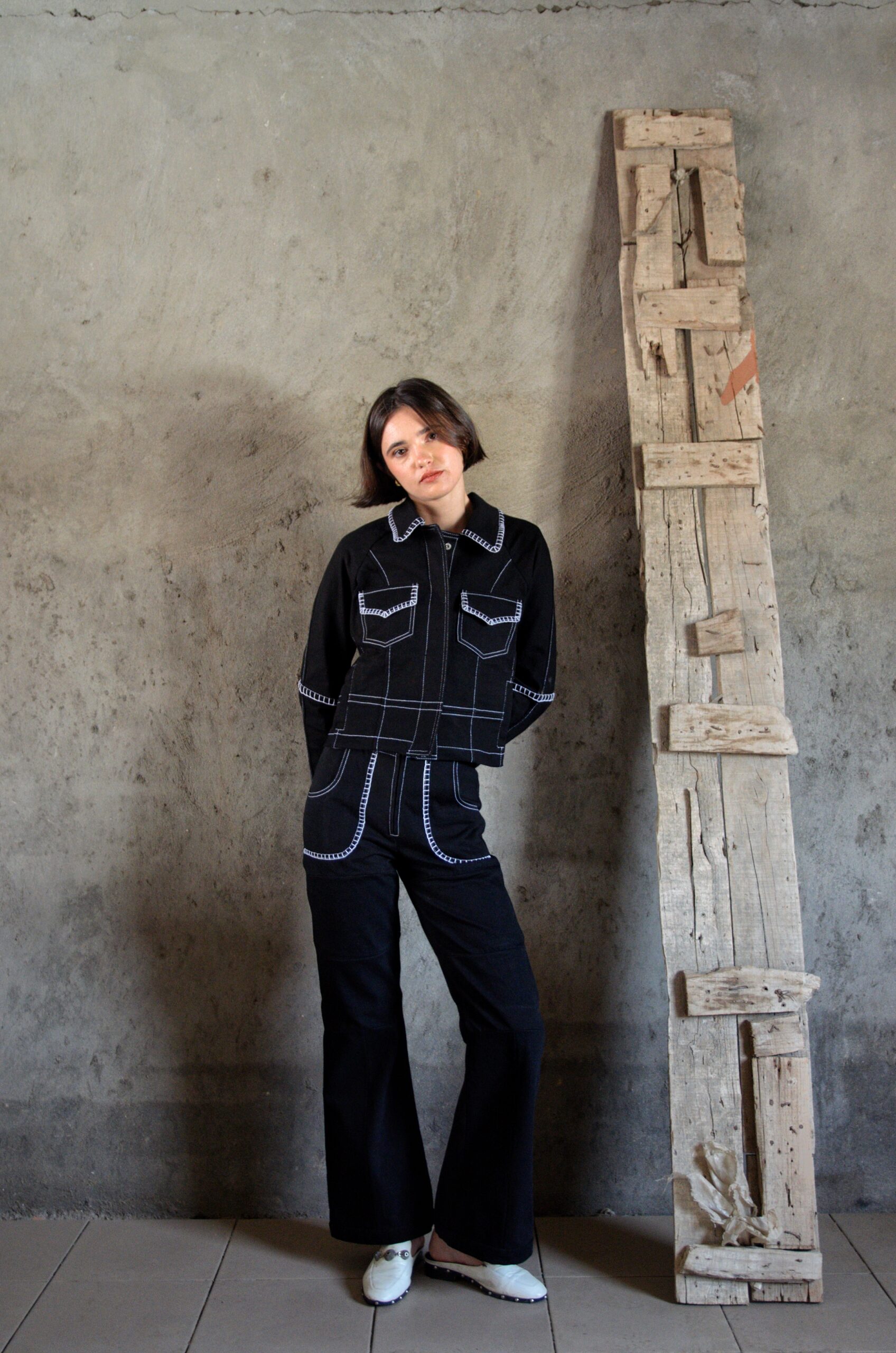 Veste Lova noire en denim portée en silhouette complète avec pantalon assorti et surpiqûres blanches